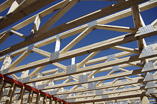 Skyward view of second story trusses with the blue sky behind them