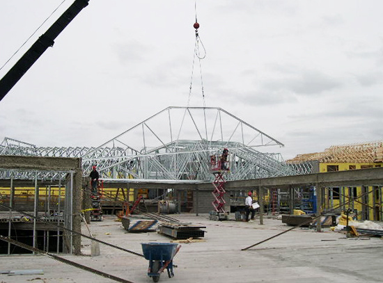 A steel roof truss is put into place on a new building